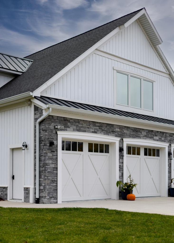 Modern Grand Haven home exterior with white siding, stone facade, and double garage doors