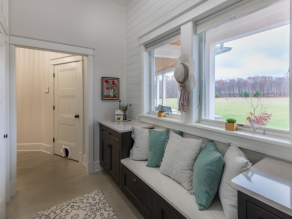 Mudroom with light colors, pillows, and window view in a Holland lake-access home.