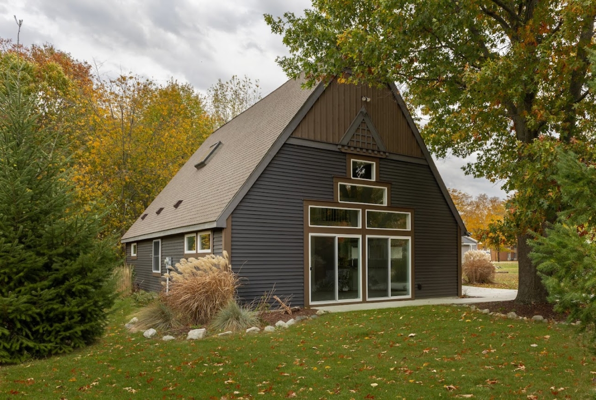 A-frame Holland lake home surrounded by fall foliage and green lawn.