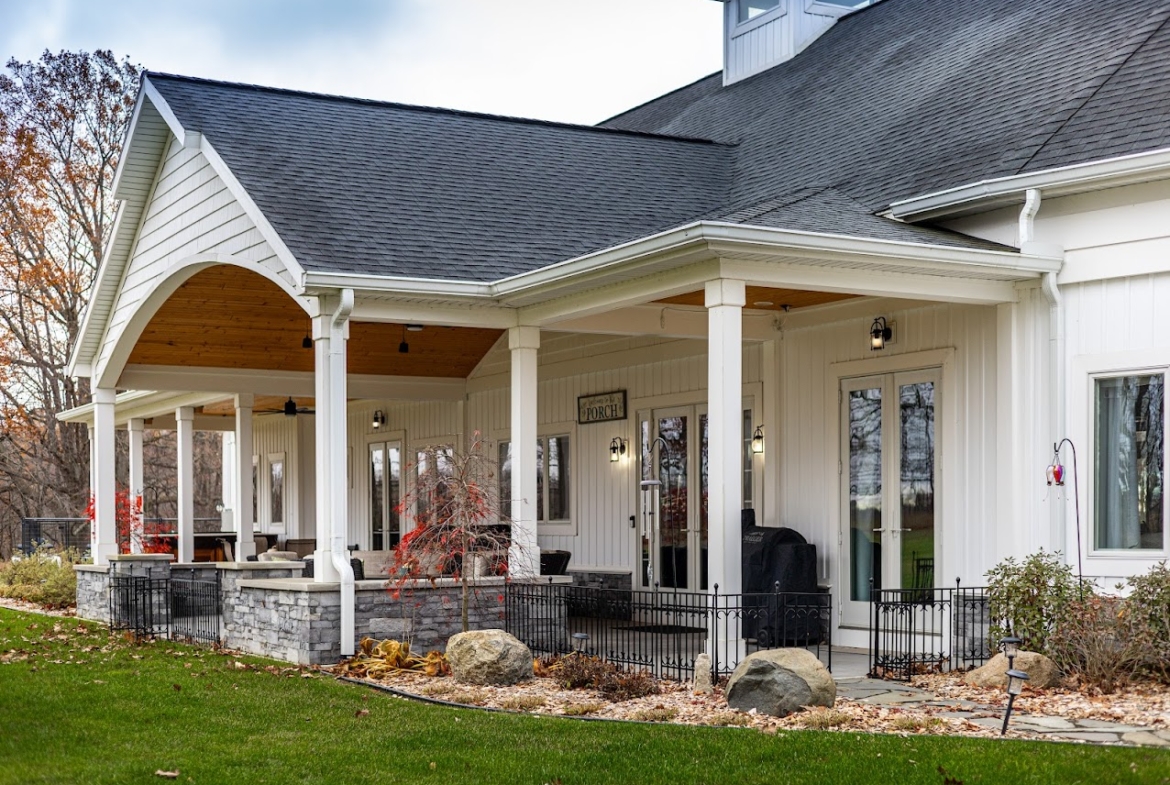 Covered front porch with white columns and stone base at a Holland lake home.