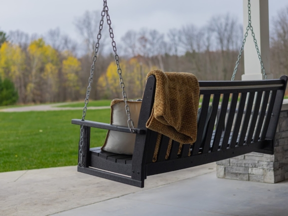 Porch swing with blanket overlooking a winter landscape at a Holland lake home.