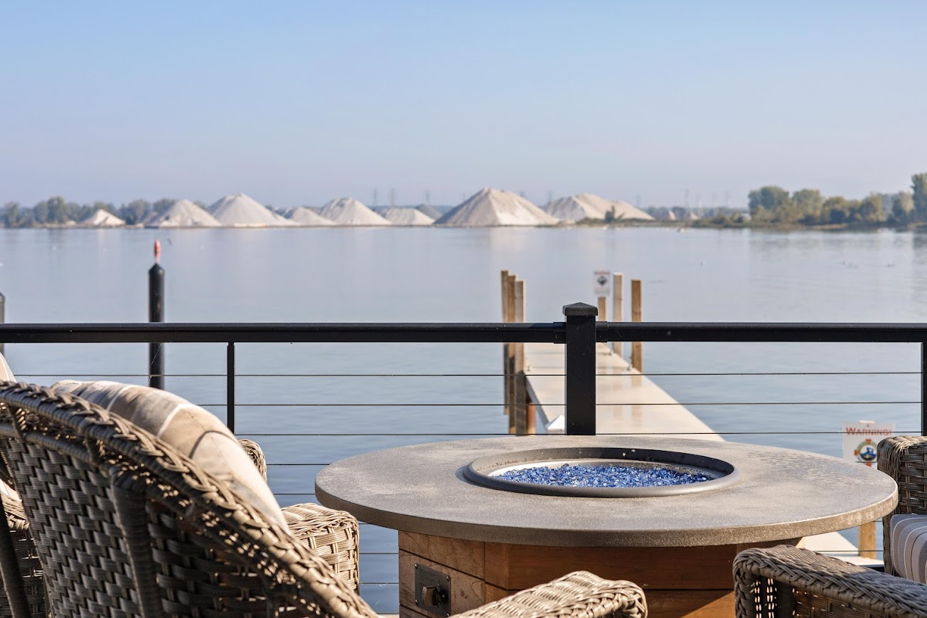 Lakeshore home deck with fire table, seating, and dock on a West Michigan waterway