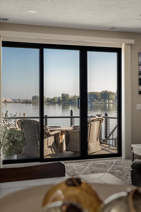 Lake view from living room with sliding doors and outdoor seating in Spring Lake home