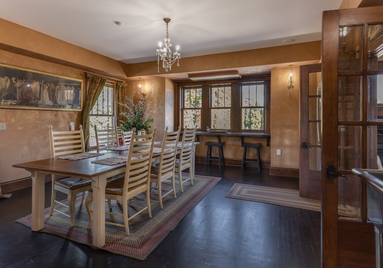 Warm formal dining room in a Grand Haven home with long farmhouse table and traditional windows.