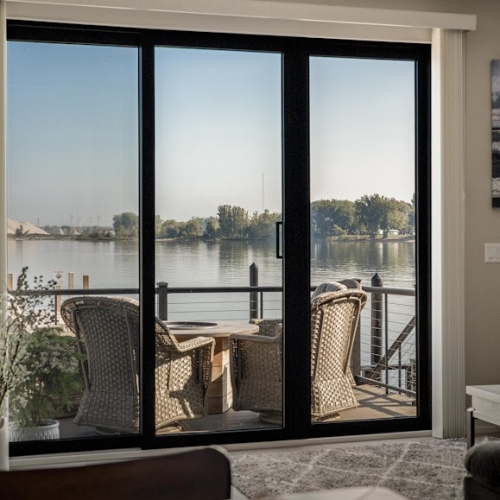 Lake view from living room with sliding doors and outdoor seating in Spring Lake home
